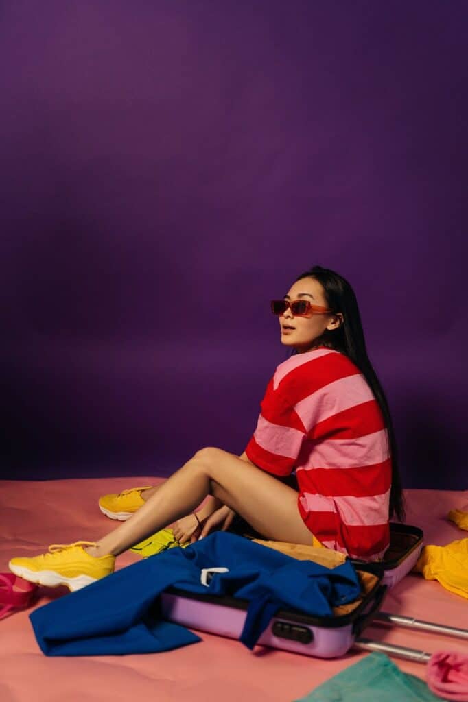 How to pack a suitcase Photo by Victoria Strelka_ph: https://www.pexels.com/photo/woman-sitting-in-violet-suitcase-full-of-colourful-clothing-11034412/