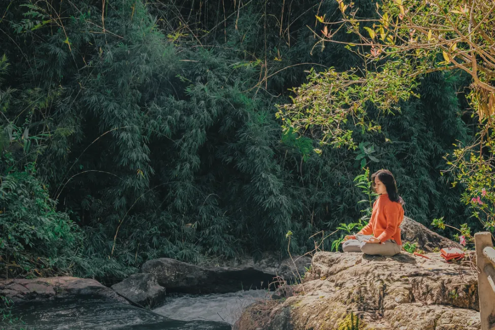 woman meditating outside - meditation retreat packing list